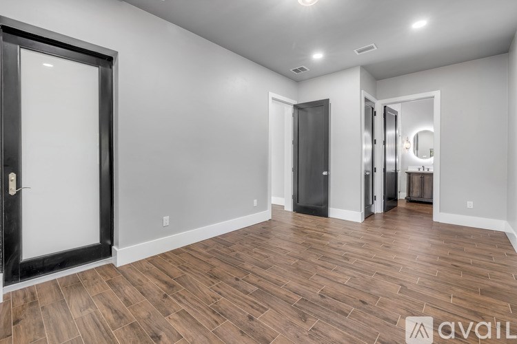 A spacious room with wooden flooring and a large mirror on the wall.