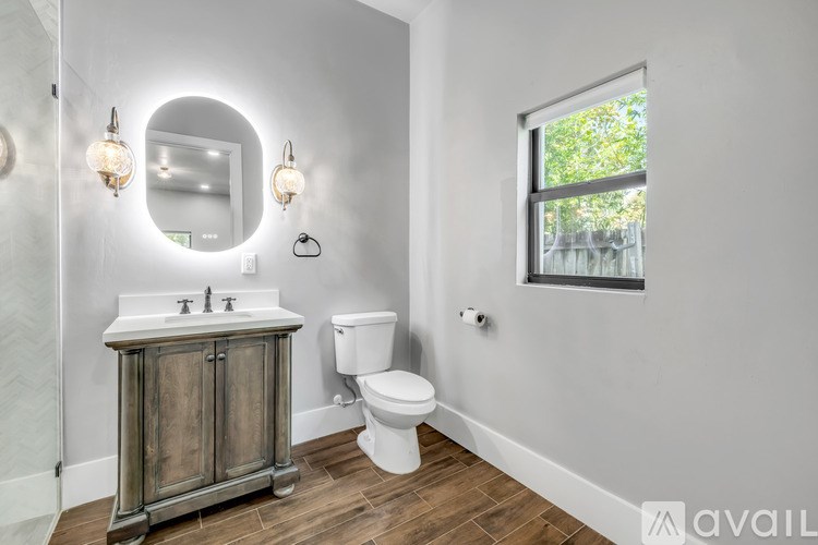 A bathroom with a wooden cabinet, a white toilet, and a round mirror.