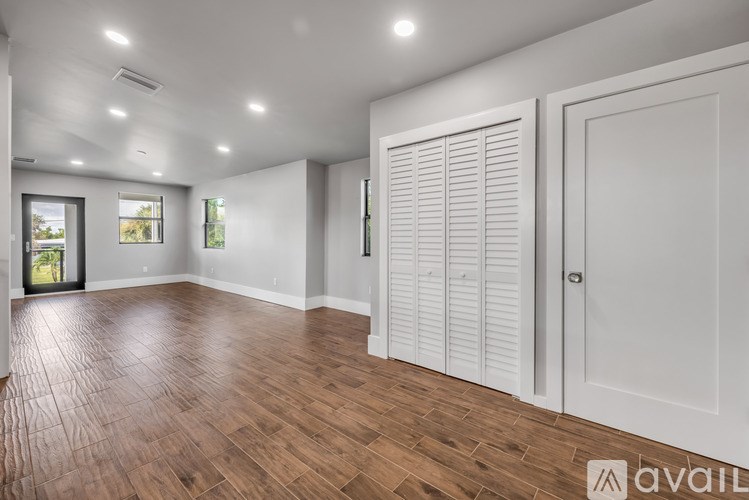 A spacious room with wooden flooring and white walls.