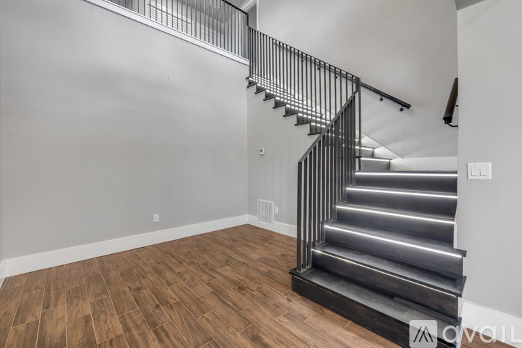 A wooden staircase with metal railings in a room with white walls.