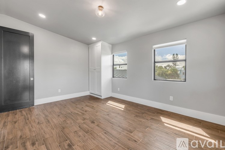 A spacious room with wooden flooring and a large window showing an outdoor view.