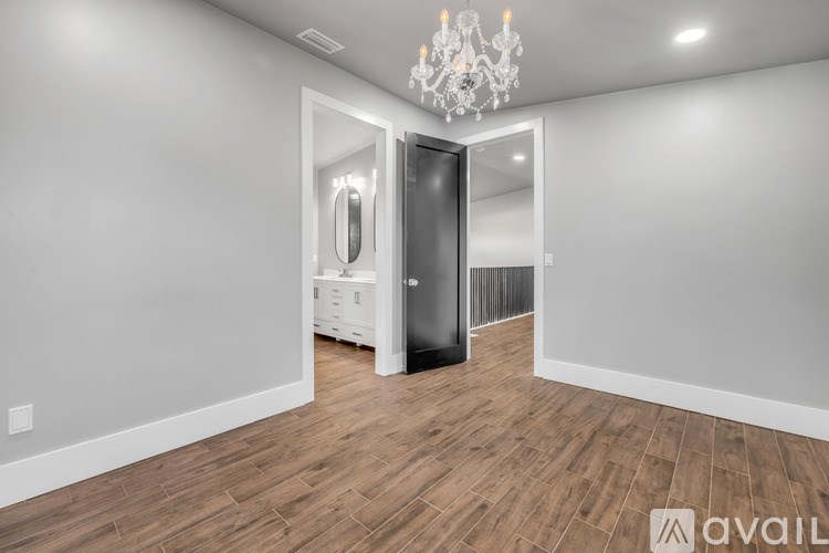 A spacious room with a chandelier, a large mirror, and a black refrigerator.
