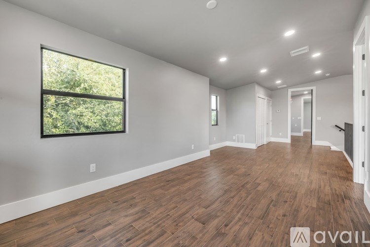 A spacious room with wooden flooring and a large window.