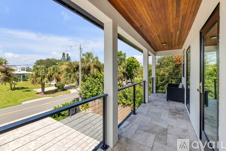 A balcony with a wooden ceiling and a view of a street and trees.