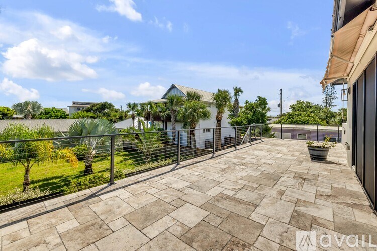 A patio with a stone floor and a metal fence.