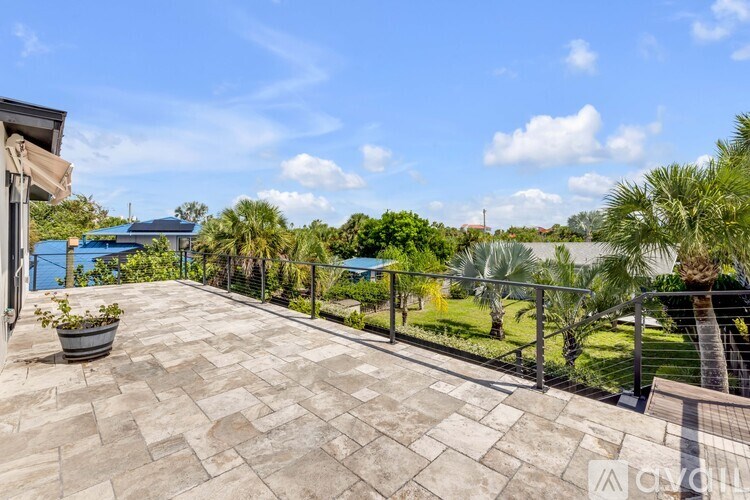 A balcony with a potted plant and a view of a green lawn and trees.