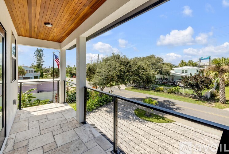 A balcony with a wooden ceiling and a view of a street and houses.