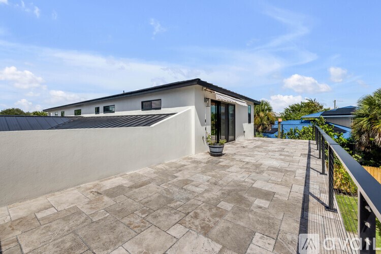 A modern house with a tiled patio and a metal railing.