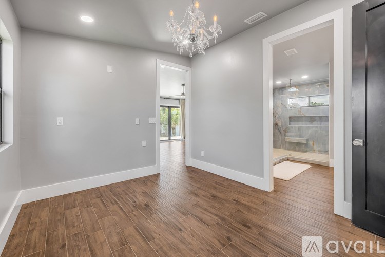 A spacious room with wooden flooring and a chandelier.