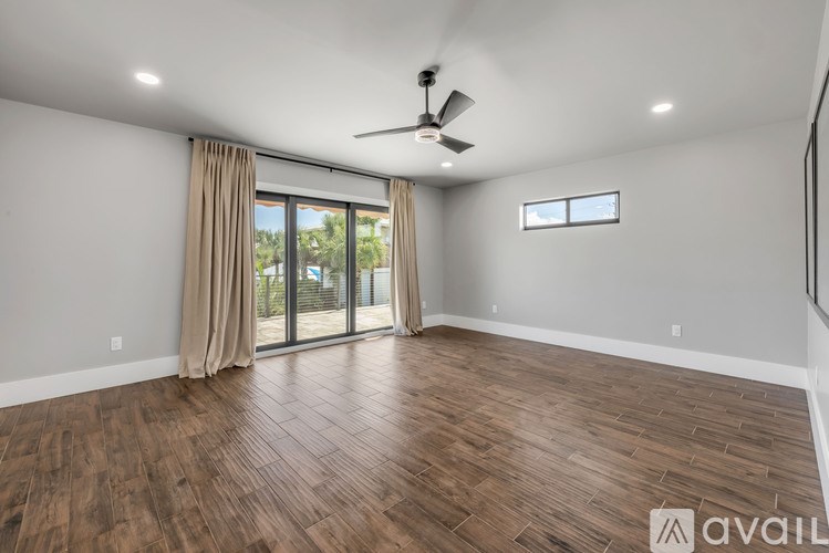 A spacious room with wooden flooring and a ceiling fan.