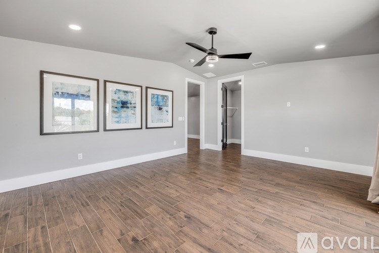 A room with a ceiling fan and three framed pictures on the wall.