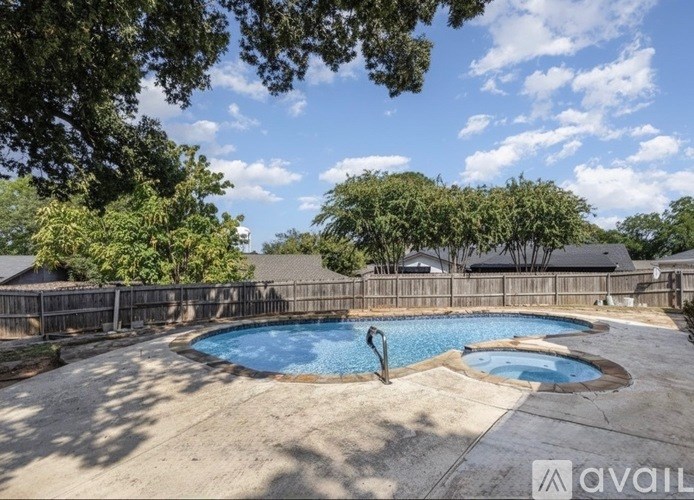 A pool surrounded by a wooden fence and trees.