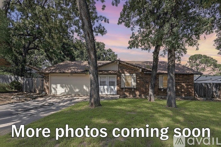 A house with a garage is surrounded by trees.