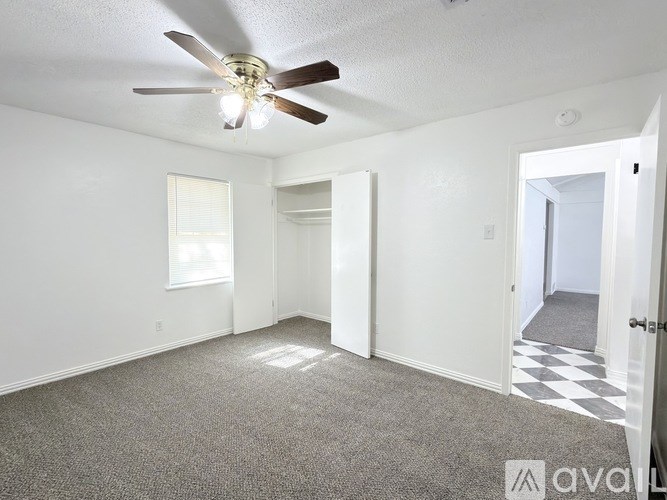 A room with a ceiling fan and carpeted floor.