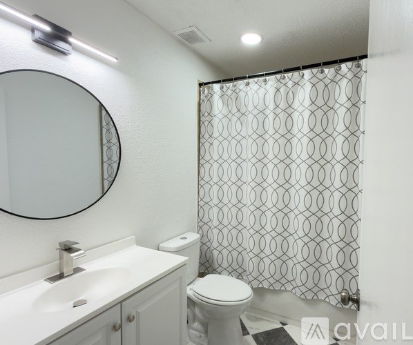 A bathroom with a toilet, sink, mirror, and shower curtain.