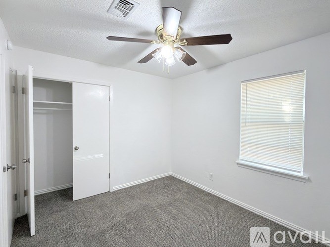 A room with a ceiling fan and a window with blinds.
