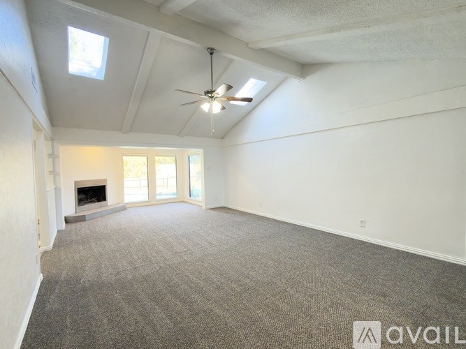 A spacious room with a fireplace and a ceiling fan.
