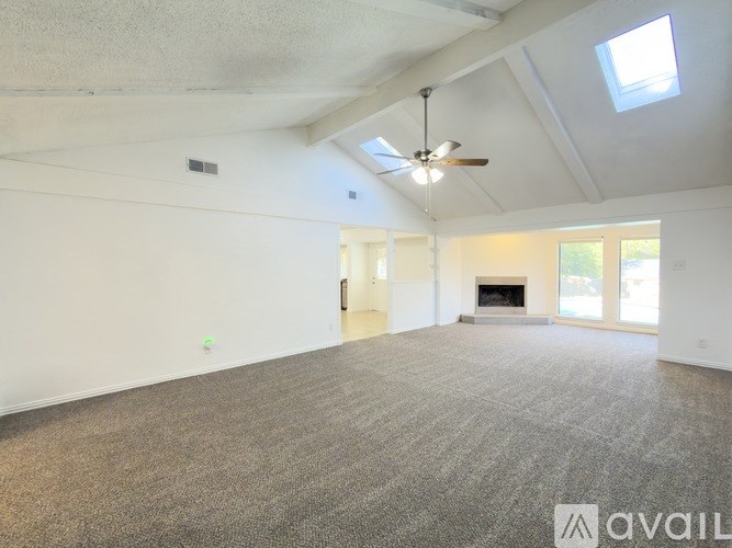 A spacious room with a fireplace and a ceiling fan.