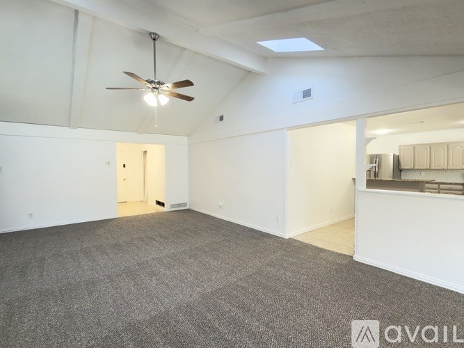 A spacious room with a ceiling fan and carpeted floor.