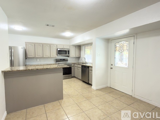 A kitchen with a refrigerator, microwave, oven, and sink.