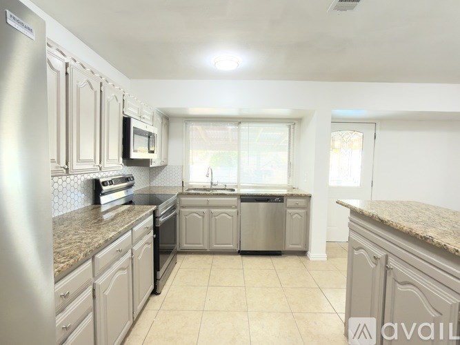 A kitchen with white cabinets and a granite countertop.