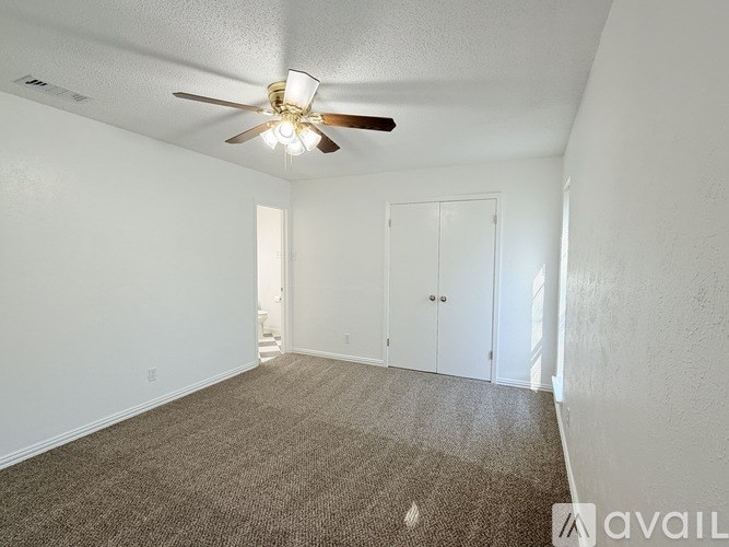 A room with a ceiling fan and carpeted floor.