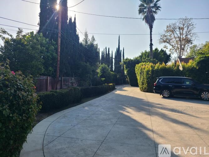 A sunny day in a residential area with a black car parked on the street.