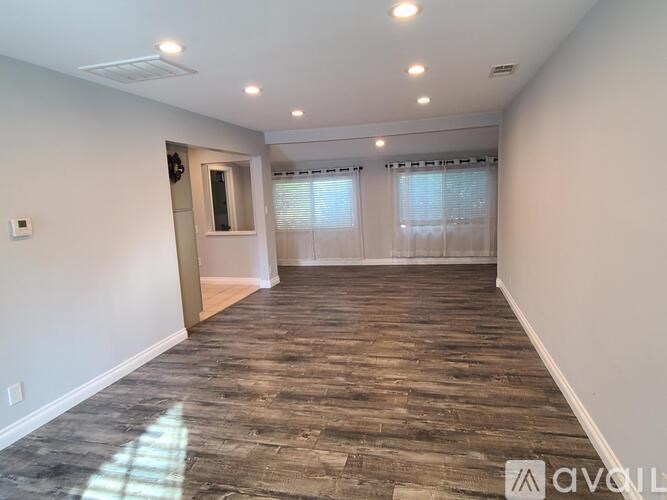 A room with wooden flooring and a window with blinds.