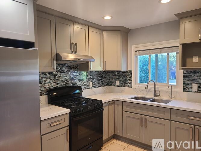 A kitchen with a black stove top oven and a stainless steel refrigerator.