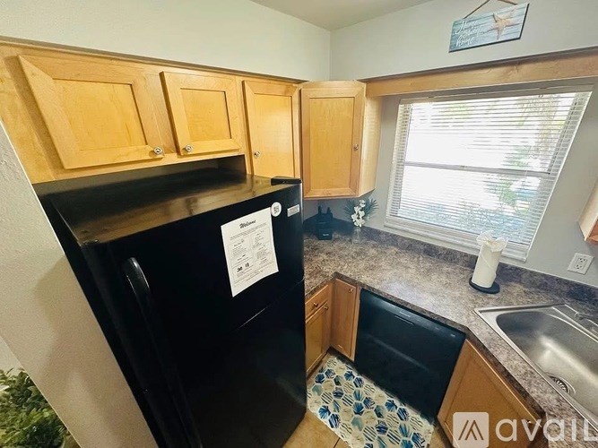 A kitchen with a black fridge and wooden cabinets.