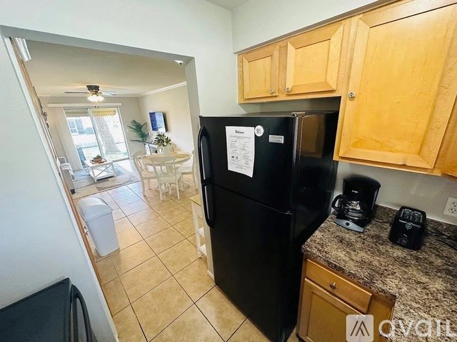 A black fridge in a kitchen with wooden cabinets.