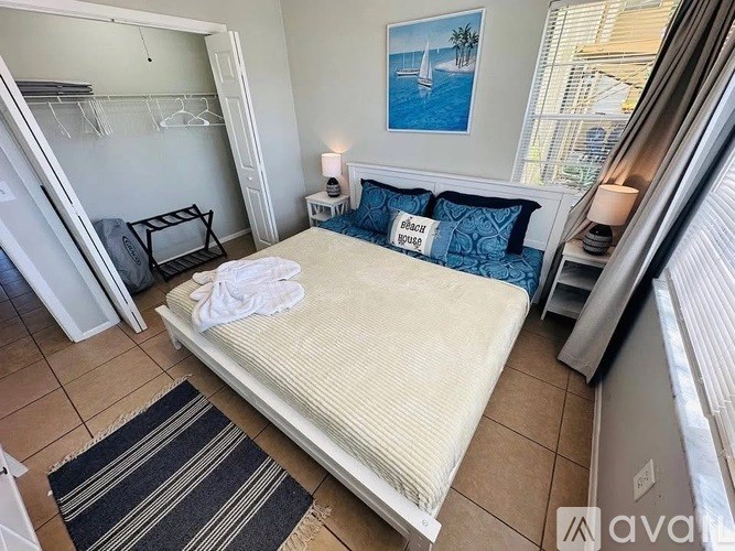 A bedroom with a bed, pillows, and a painting on the wall.