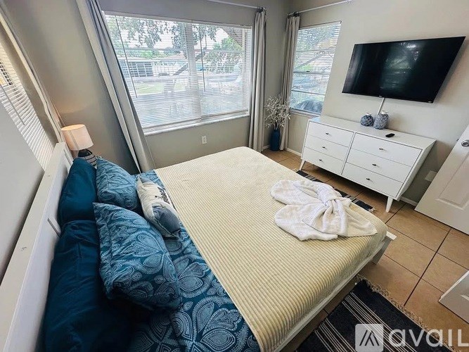 A bedroom with a bed, a television, and a window with a view of the outside.
