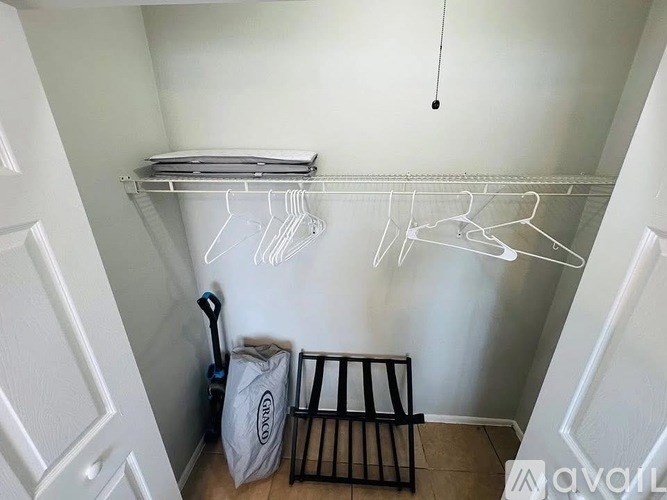A white closet with clothes hangers and a bag on the floor.