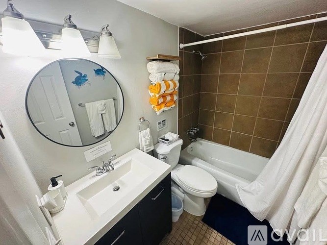 A bathroom with a white sink, toilet, and a brown tiled shower.