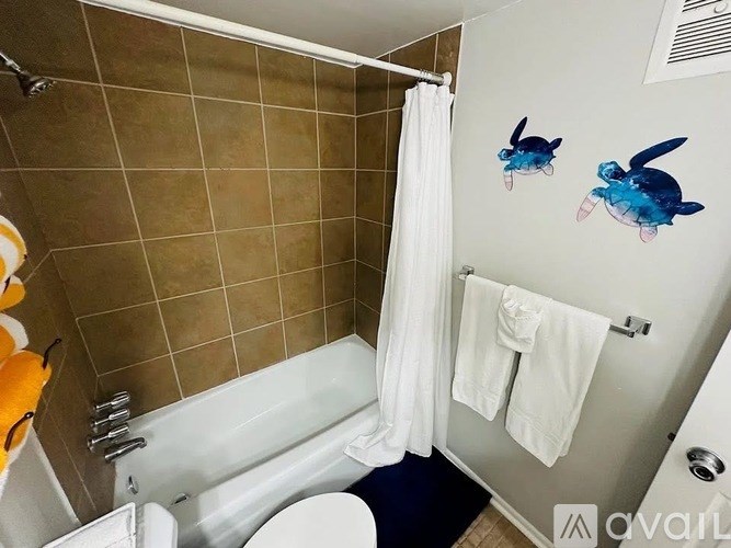 A bathroom with a white tub, toilet, and towels.
