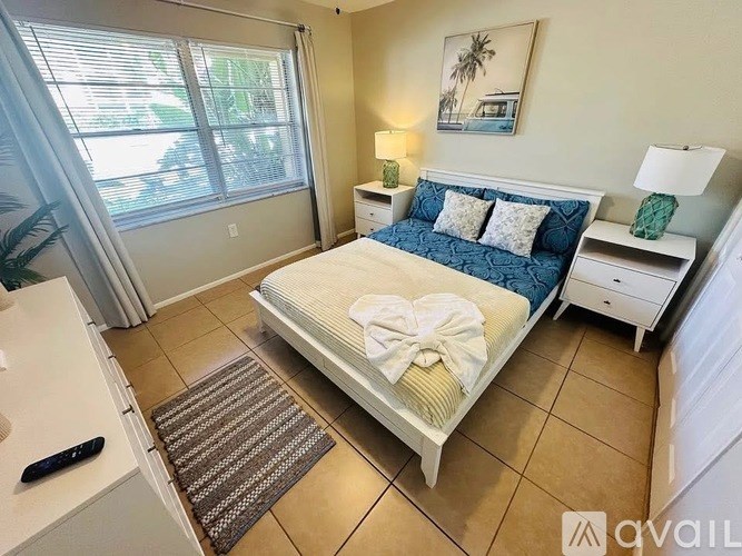 A bedroom with a bed, nightstands, and a window with blinds.