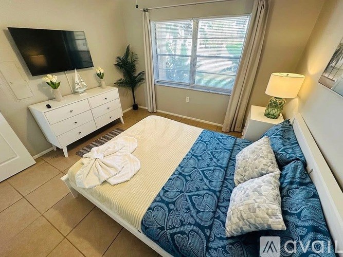 A bedroom with a bed, dresser, and window.