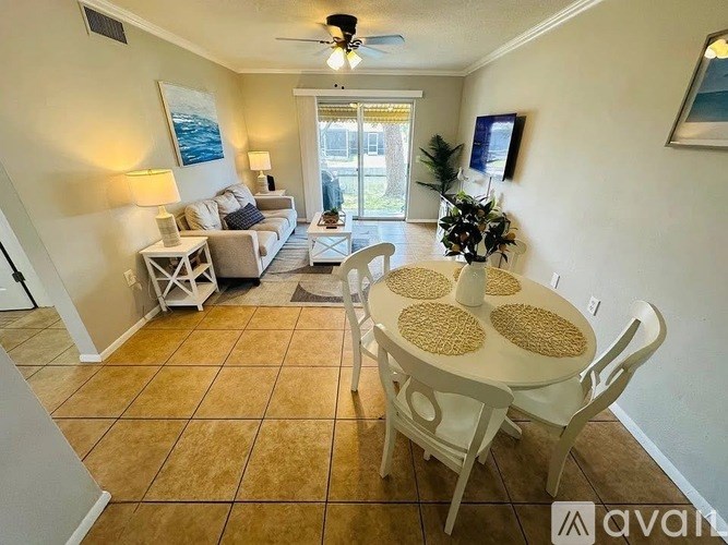 A living room with a white table and chairs, a ceiling fan, and a painting on the wall.