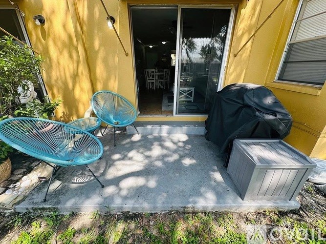 A patio with a blue chair and a black cover.