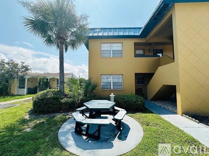 A yellow house with a picnic table in front.