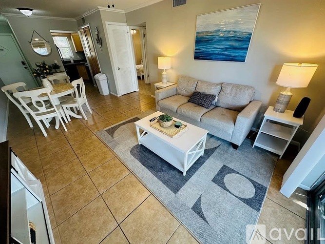 A living room with a white couch, a coffee table, and a painting on the wall.