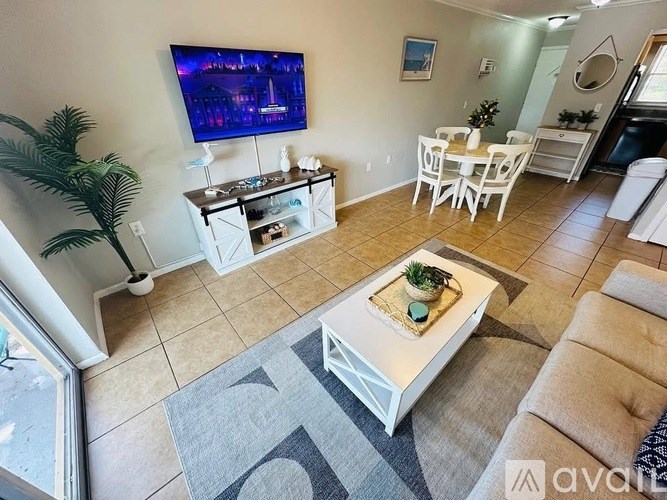 A living room with a television, a coffee table, and a dining table.