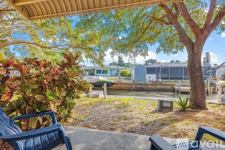 A blue bench is in front of a tree and a sign.