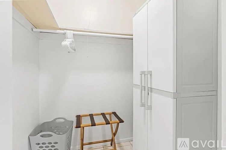 A room with a white wall, a wooden chair, and a white cabinet.