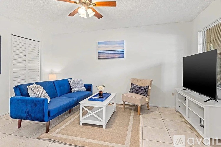A living room with a blue couch, a white coffee table, and a television.