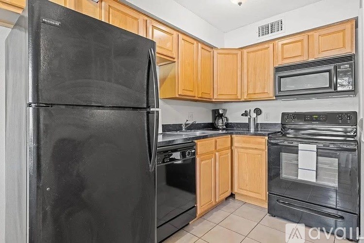 A kitchen with black appliances and wooden cabinets.