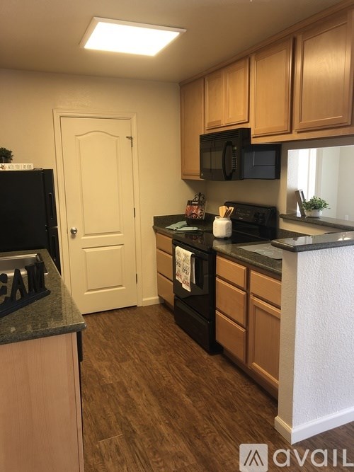 A kitchen with black appliances and wooden cabinets.
