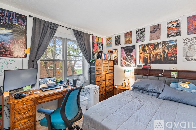 A bedroom with a bed, desk, chair, and posters on the wall.