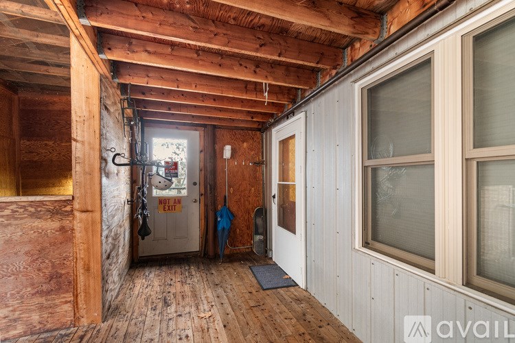 A room with wooden walls and ceiling, a door with a sign that says "EXIT" and a window on the right side.
